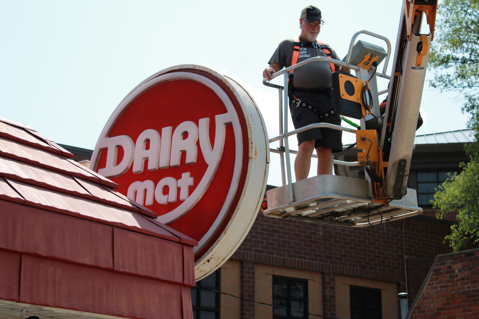 Eddie in the boom lift working on the Dairy Mat sign. High Lighting Service Company.